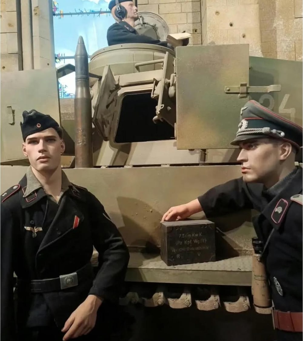 Schwarze Panzerjacken mit rosafarbenem Vorstoß, vor dem Turm. Rechts die Kiste für die 7,5-cm-KwK-Munition.